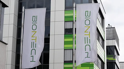 Außenansicht des modernen Büro- und Laborgebäudes von Biontech in Mainz mit zwei  Fahnen, auf denen das grüne Firmenlogo „Biontech“ zu sehen ist