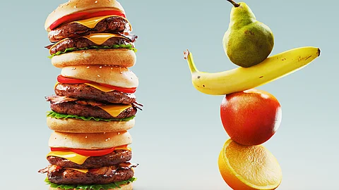 Zwei gestapelte Türme aus Lebensmitteln: links ein Turm aus Burgern, rechts ein Turm aus frischem Obst auf weißem Hintergrund