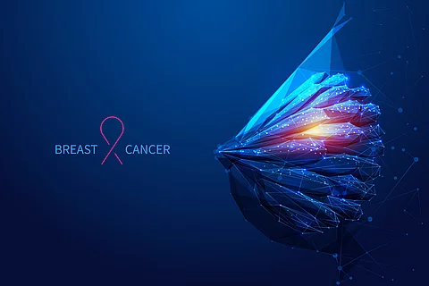 Abstrakte, polygonale Darstellung einer Brust in Blau- und Orangetönen mit vernetzten Linien und Lichtpunkten, daneben ein rosa Band und der Schriftzug „Breast Cancer“.