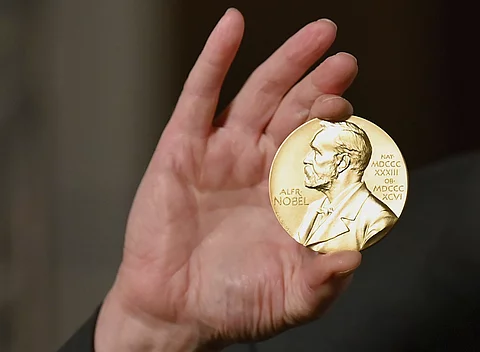 Eine Hand hält eien Nobelmedaille hoch