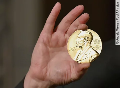 Eine Hand hält eien Nobelmedaille hoch