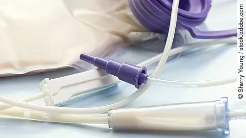 Nahaufnahme eines enteralen Ernährungssystems mit Schläuchen, Anschlussstück und einem mit Nährlösung gefüllten Beutel auf hellem Untergrund.
