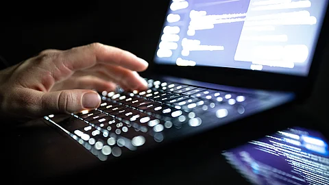 Eine Person tippt mit den Fingern auf einer beleuchteten Laptop-Tastatur.