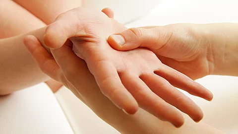 Nahaufnahme zweier Hände, bei der eine Handfläche durch sanften Druck mit den Fingern der anderen Hand stimuliert wird Nahaufnahme zweier Hände, bei der eine Handfläche durch sanften Druck mit den Fingern der anderen Hand stimuliert wird
