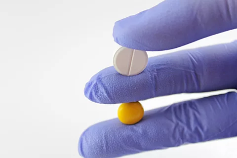 Hand hält zwei verschiedene Tabletten 