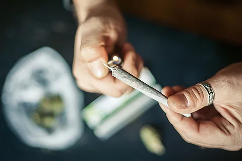 Close up of addict lighting up marijuana joint with lighter