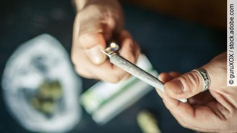 Close up of addict lighting up marijuana joint with lighter