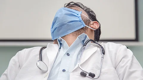 Ein überarbeiteter Arzt macht auf einem Stuhl im Krankenhaus ein Nickerchen