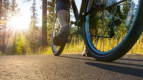 Nahaufnahme: Fahrhrad auf einem Asphaltweg bei untergehender Sonne