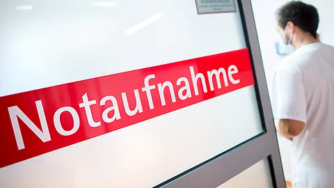 Ein Krankenpfleger steht in einem Braunschweiger Krankenhaus neben einer Glastür mit der Aufschrift «Notaufnahme».