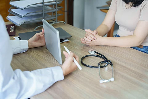 An Asian female doctor shows the patient a computer tablet to se