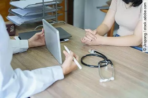 An Asian female doctor shows the patient a computer tablet to se
