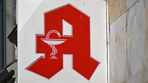Rotes Apotheken-Logo an einer Hauswand.