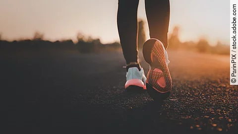 Young woman doing exercise walking and run on country road in th