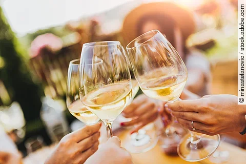People clinking glasses with wine on the summer terrace of cafe 