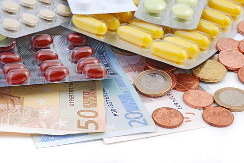 Drei Tablettenblister liegen auf Geldscheinen und Münzen.