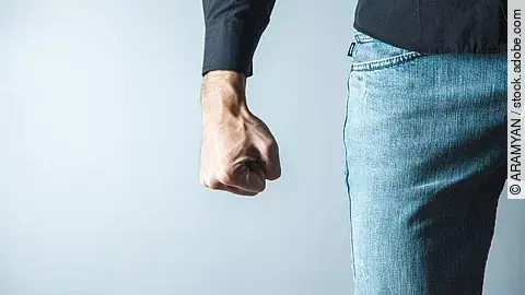 Androhung von körperlicher Gewalt: Nahaufnahme eines Unterkörpers und eines Arms, bei dem eine Faust angespannt nach unten zeigt 