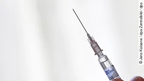 Grippeschutzimpfung - eine Hand hält eine Spritze zur intramuskulären Injektion des Impfstoffs