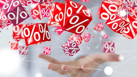 Mehrere rote Würfel mit weißen Prozentzeichen schweben über einer geöffneten Hand