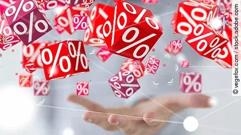 Mehrere rote Würfel mit weißen Prozentzeichen schweben über einer geöffneten Hand