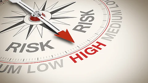 Nahaufnahme eines Messinstruments mit Zeiger, der zwischen den Bereichen „Low Risk“ und „High Risk“ steht,