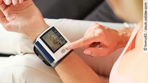 Eine Person misst ihren Blutdruck mit einem elektronischen Handgelenk-Blutdruckmessgerät.