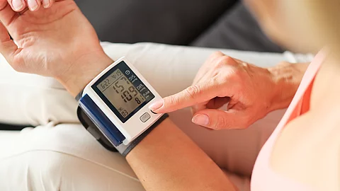Eine Person misst ihren Blutdruck mit einem elektronischen Handgelenk-Blutdruckmessgerät.