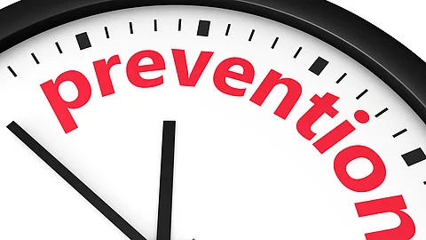 Nahaufnahme einer Uhr, auf deren Zifferblatt das Wort ‚prevention‘ in roten Buchstaben steht.
