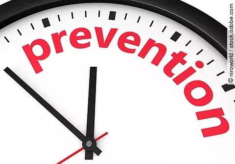 Nahaufnahme einer Uhr, auf deren Zifferblatt das Wort ‚prevention‘ in roten Buchstaben steht.