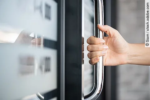 Closeup woman hand holding the door bar to open the door with gl