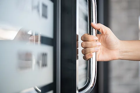 Closeup woman hand holding the door bar to open the door with gl