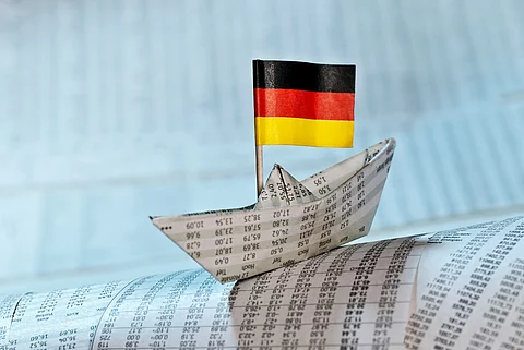 Papierschiff mit deutscher Flagge auf Börsennachrichten Papierschiffchen mit deutscher Flagge