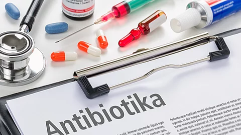 Mehrere Packungen und Blister von Antibiotika liegen nebeneinander, im Vordergrund ist der Schriftzug „Antibiotika“ zu sehen.