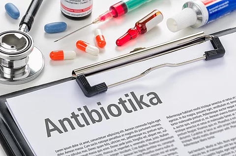 Mehrere Packungen und Blister von Antibiotika liegen nebeneinander, im Vordergrund ist der Schriftzug „Antibiotika“ zu sehen.