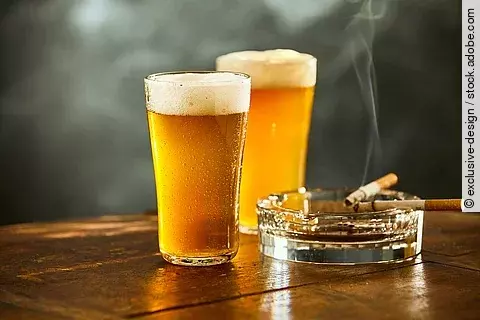 Biergläser und rauchende Zigarette im Aschenbecher