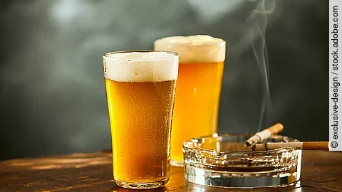Biergläser und rauchende Zigarette im Aschenbecher