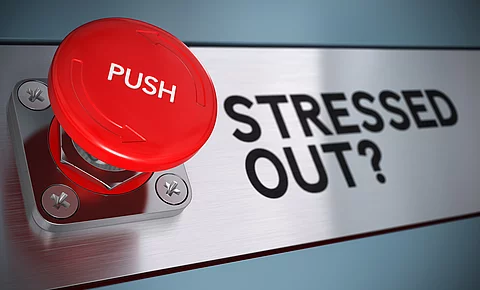 Ein großes rotes Notfallknopf mit der Aufschrift „PUSH“ ist prominent im Vordergrund zu sehen. Daneben steht in großen schwarzen Buchstaben die Frage „STRESSED OUT?“ auf einer metallisch glänzenden Oberfläche. Das Bild vermittelt den Eindruck von Alarm und Handlungsdruck, passend zum Thema Stress und Burnout.