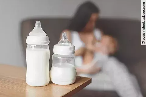 Bottles with breast milk on the background of mother holding in 