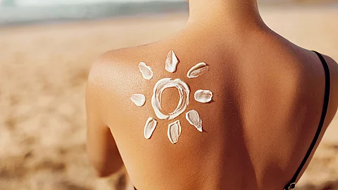 Oberer Rücken einer Person am Strand, auf dem mit Sonnencreme ein Sonnensymbol aufgetragen wurde.