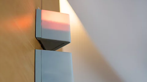 Zwei kantige Signalleuchten an einer Holzvertäfelung, die obere leuchtet rot – Symbol für Alarm oder Besetztanzeige in einem Krankenhaus. Zwei kantige Signalleuchten an einer Holzvertäfelung, die obere leuchtet rot – Symbol für Alarm oder Besetztanzeige in einem Krankenhaus.