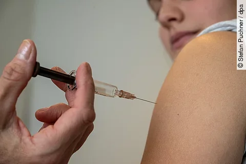 Eine medizinische Fachkraft setzt einer Person eine Injektion in den Oberarm Eine medizinische Fachkraft setzt einer Person eine Injektion in den Oberarm