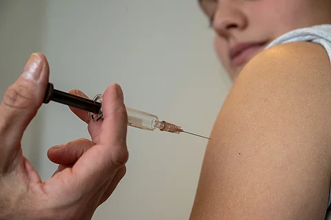 Eine medizinische Fachkraft setzt einer Person eine Injektion in den Oberarm