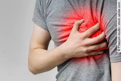 Mann fasst sich an Brust in rotgefärbter Herzgegend