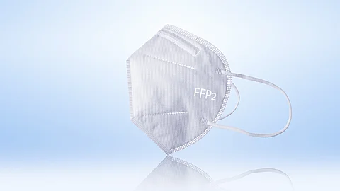 Weiße FFP2-Atemschutzmaske liegt vor hellem Hintergrund und ist seitlich dargestellt.