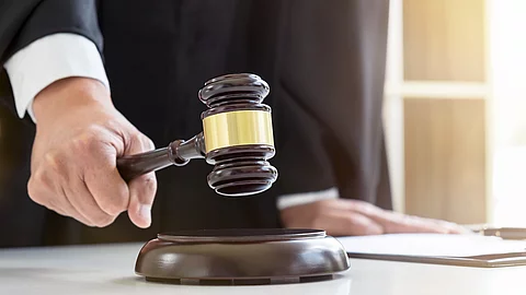 Close up of Male lawyer or judge hand's striking the gavel on sounding block, working with Law books, report the case on table in modern office, Law and justice concept