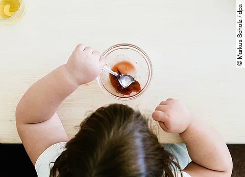 Ein übergewichtiges Kind sitzt am Tisch und isst.