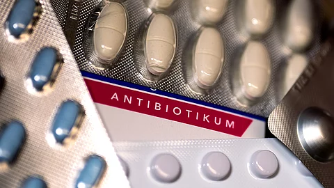 Nahaufnahme mehrerer Blisterpackungen mit Antibiotika-Tabletten in unterschiedlichen Farben. Im Hintergrund ist das Wort „Antibiotikum“ auf einer Verpackung deutlich sichtbar.