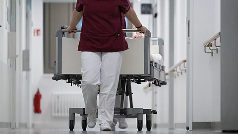 Eine Krankenpflegerin und ein Krankenpfleger schieben ein Krankenbett durch den Gang einer Station eines Krankenhauses. Eine Krankenpflegerin und ein Krankenpfleger schieben ein Krankenbett durch den Gang einer Station eines Krankenhauses.