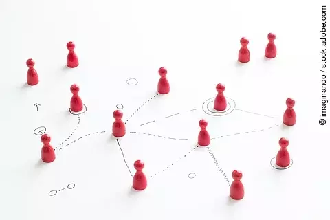Mehrere rote Spielfiguren stehen auf einem weißen Hintergrund; gezeichnete Linien verbinden sie miteinander und symbolisieren ein Netzwerk oder koordinierte Zusammenarbeit.