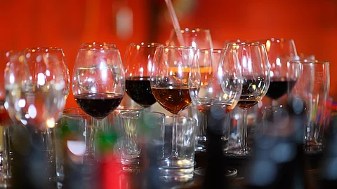 Leere und halbleere Gläser mit alkoholischen Getränken stehen in einer Bar auf einem Tresen. 